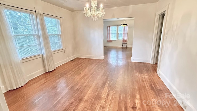 spare room with wood-type flooring, an inviting chandelier, and ornamental molding