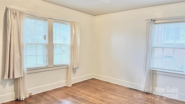 unfurnished room with crown molding, a wealth of natural light, and hardwood / wood-style flooring