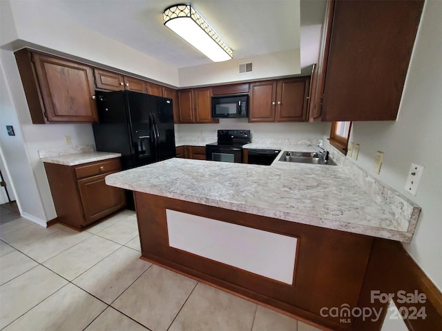 kitchen with dark brown cabinets, black appliances, kitchen peninsula, sink, and light tile patterned flooring