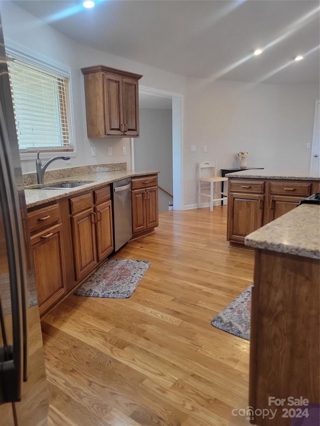 kitchen featuring light stone counters, light hardwood / wood-style floors, sink, and stainless steel appliances