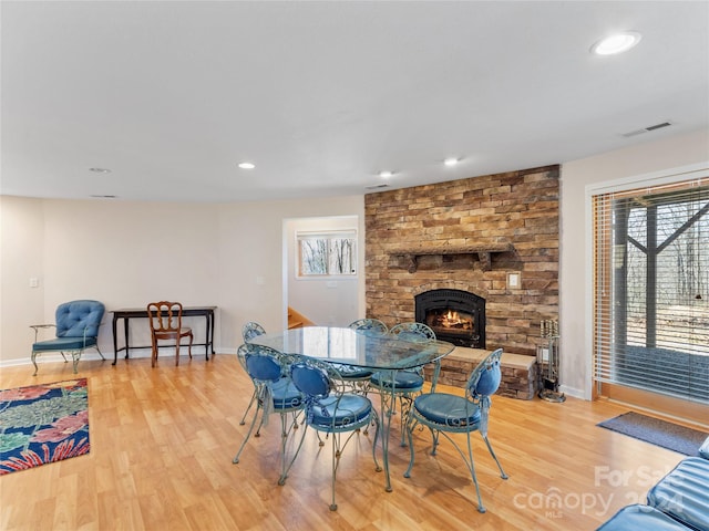 dining space featuring plenty of natural light, a stone fireplace, and light hardwood / wood-style floors