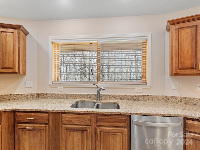 kitchen with dishwasher, sink, and light stone countertops