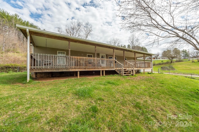 rear view of house with a wooden deck and a lawn