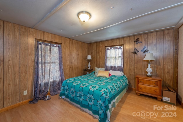 bedroom featuring wooden walls and light hardwood / wood-style flooring