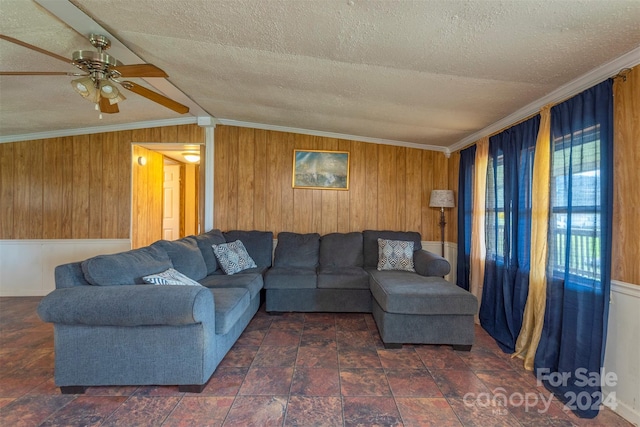 living room featuring dark tile flooring, wood walls, ceiling fan, and vaulted ceiling