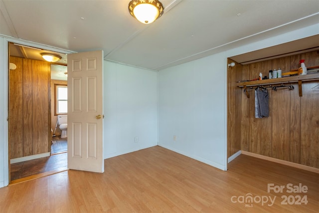 spare room featuring wood walls and light wood-type flooring