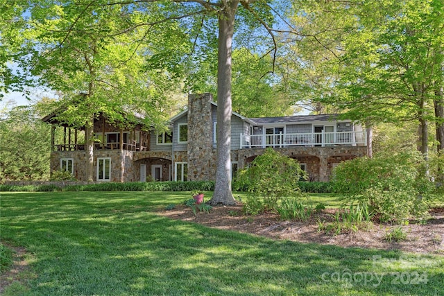 rear view of house featuring a balcony and a lawn