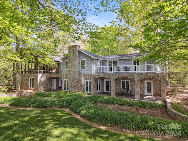 rear view of property featuring a yard and a balcony