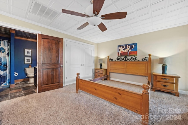 bedroom featuring dark tile floors, ensuite bath, and ceiling fan