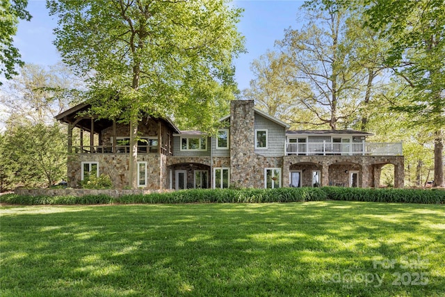 rear view of property with a lawn, a chimney, and a balcony