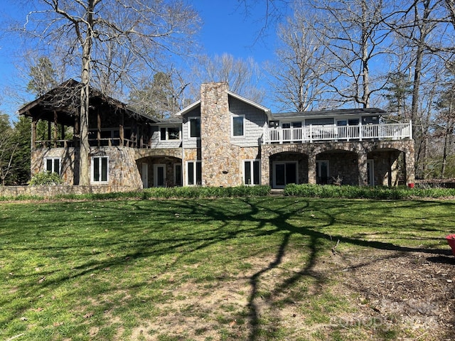 back of property featuring a yard, a chimney, and stone siding