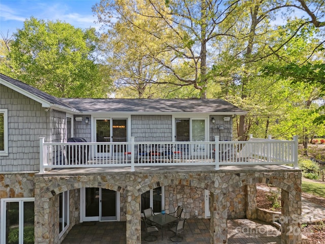 rear view of house featuring a balcony, a patio area, and stone siding