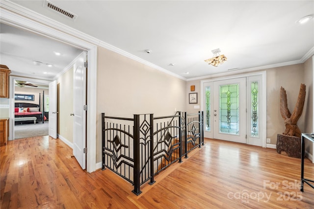 foyer entrance featuring light wood-style flooring, visible vents, and crown molding