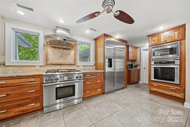 kitchen featuring built in appliances, exhaust hood, visible vents, and light stone countertops