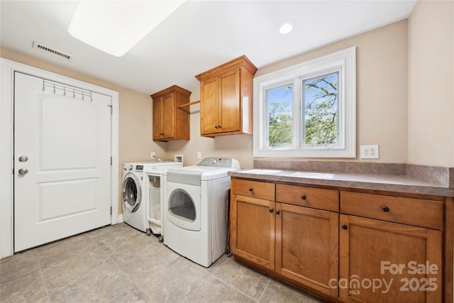 washroom featuring washer and dryer, visible vents, and cabinet space