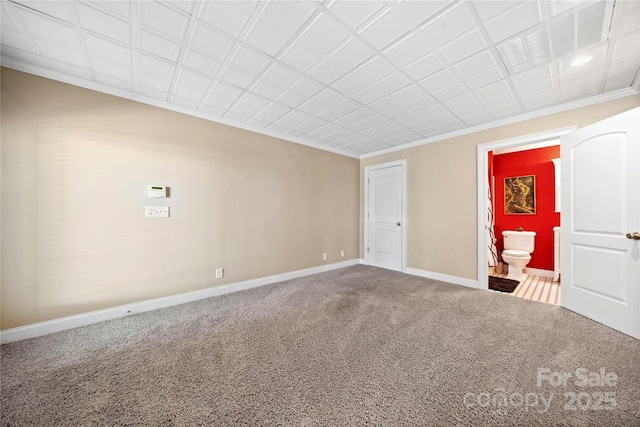 empty room featuring carpet floors, baseboards, and crown molding