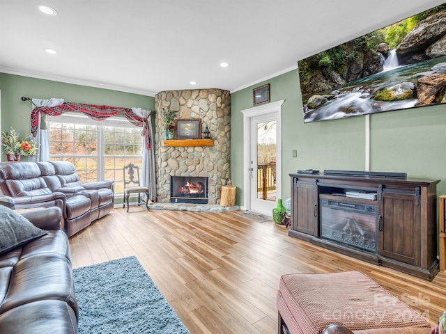 living room featuring crown molding, light hardwood / wood-style floors, and a fireplace