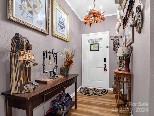 foyer with a chandelier, wood-type flooring, and ornamental molding