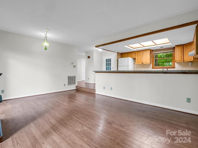 unfurnished living room with a skylight and hardwood / wood-style floors