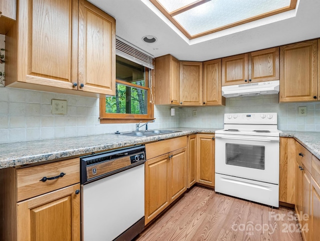 kitchen with white appliances, light stone countertops, light wood-type flooring, sink, and tasteful backsplash