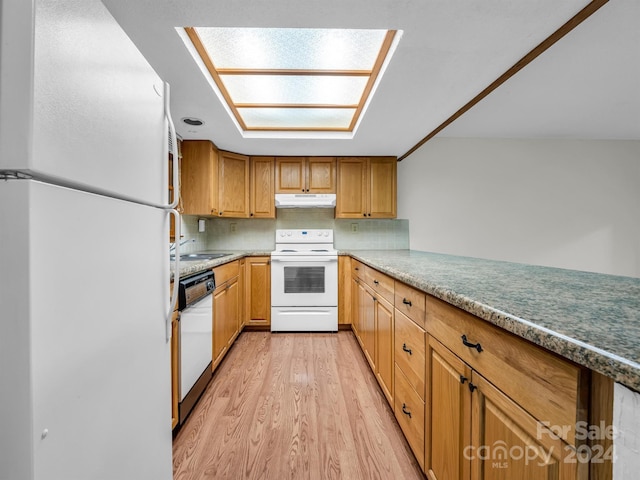 kitchen with a skylight, sink, light hardwood / wood-style floors, white appliances, and tasteful backsplash