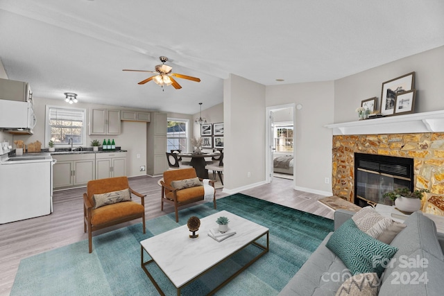 living room featuring a healthy amount of sunlight, a tiled fireplace, sink, and wood-type flooring