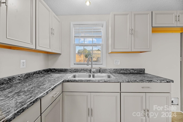 kitchen with white cabinetry, sink, and a textured ceiling