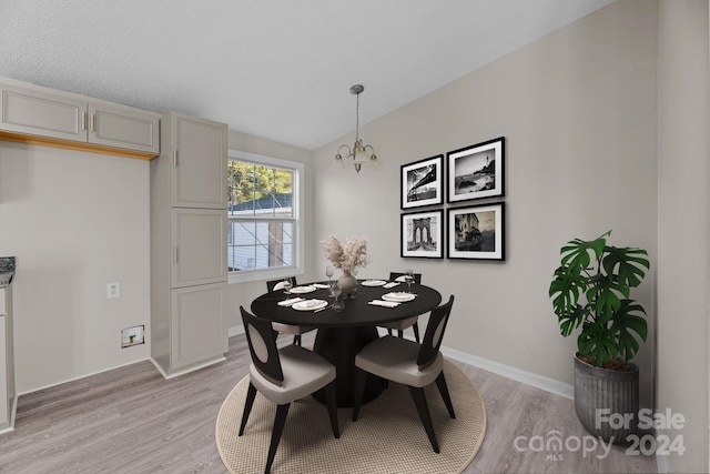 dining area with lofted ceiling, a chandelier, and light hardwood / wood-style floors