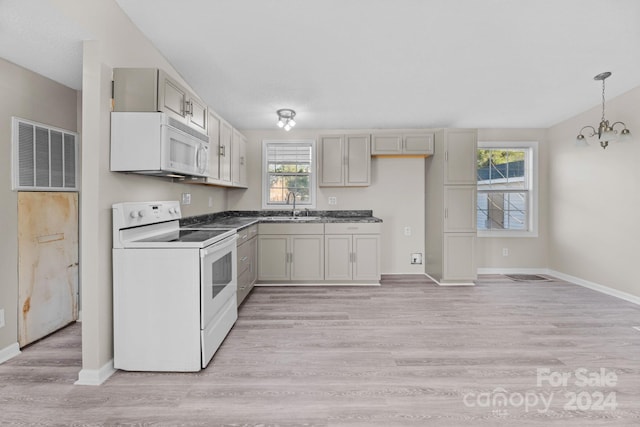 kitchen featuring sink, white appliances, an inviting chandelier, hanging light fixtures, and light wood-type flooring