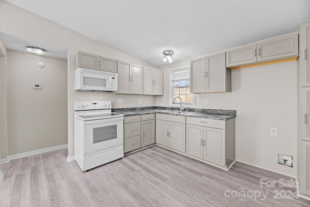 kitchen featuring sink, white appliances, gray cabinetry, light hardwood / wood-style floors, and a textured ceiling