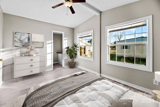 bedroom featuring ceiling fan, light hardwood / wood-style flooring, lofted ceiling with beams, and a textured ceiling