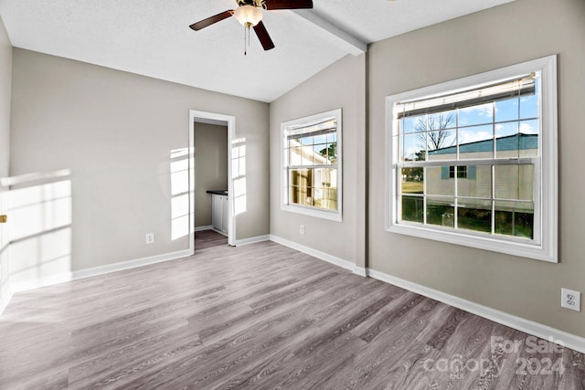 unfurnished room featuring a textured ceiling, light hardwood / wood-style flooring, lofted ceiling with beams, and ceiling fan