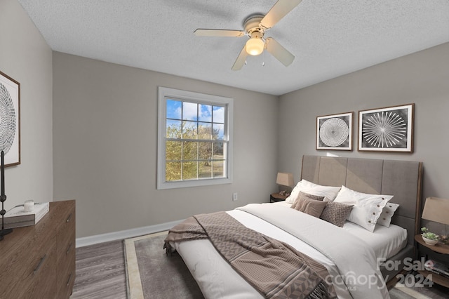 bedroom with hardwood / wood-style floors, a textured ceiling, and ceiling fan