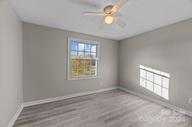 spare room with ceiling fan, light hardwood / wood-style flooring, and a textured ceiling