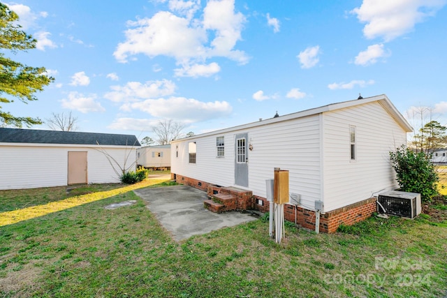 rear view of property featuring cooling unit, a lawn, and a patio area