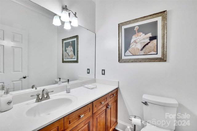 bathroom with toilet, vanity, and crown molding