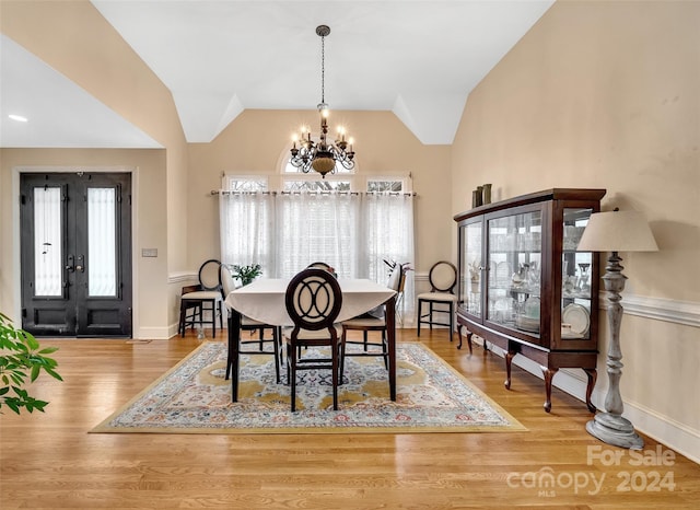 dining room with lofted ceiling, a notable chandelier, light hardwood / wood-style flooring, and plenty of natural light