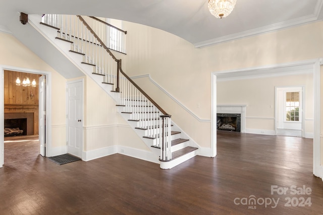 stairs featuring ornamental molding, a fireplace, dark hardwood / wood-style floors, and an inviting chandelier