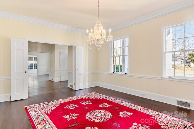 spare room featuring dark hardwood / wood-style flooring, crown molding, and a chandelier