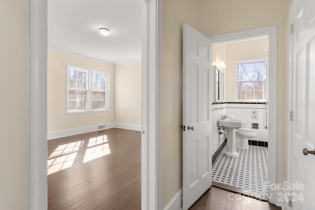 hallway with ornamental molding, tile flooring, and tile walls