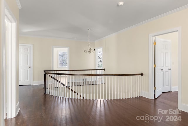 hall featuring dark wood-type flooring, an inviting chandelier, and ornamental molding