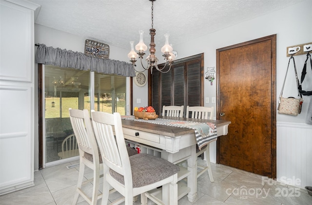 tiled dining space featuring a notable chandelier and a textured ceiling