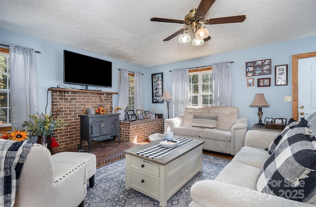 living room with a wood stove, ceiling fan, and a textured ceiling