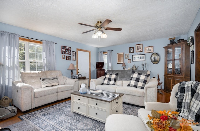 living room featuring ceiling fan, a textured ceiling, and hardwood / wood-style flooring