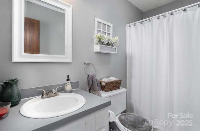 bathroom featuring vanity, toilet, and a textured ceiling