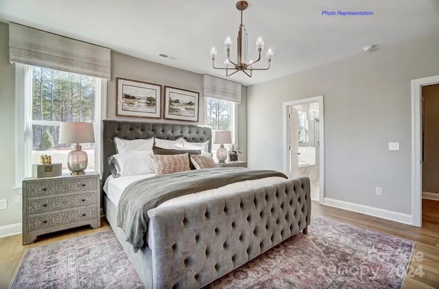 bedroom featuring an inviting chandelier, ensuite bathroom, and hardwood / wood-style floors