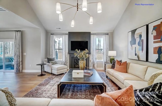 living room with a chandelier, plenty of natural light, lofted ceiling, and wood-type flooring