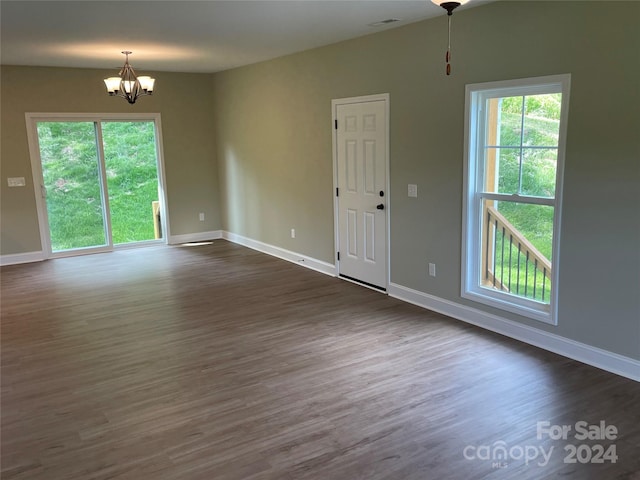 unfurnished room with dark hardwood / wood-style flooring, a healthy amount of sunlight, and a notable chandelier