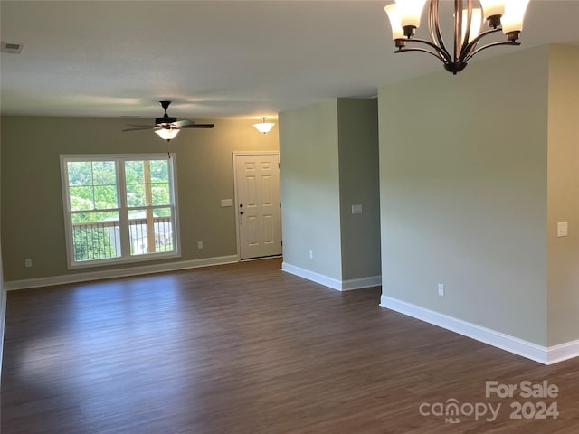 spare room featuring ceiling fan with notable chandelier and dark wood-type flooring