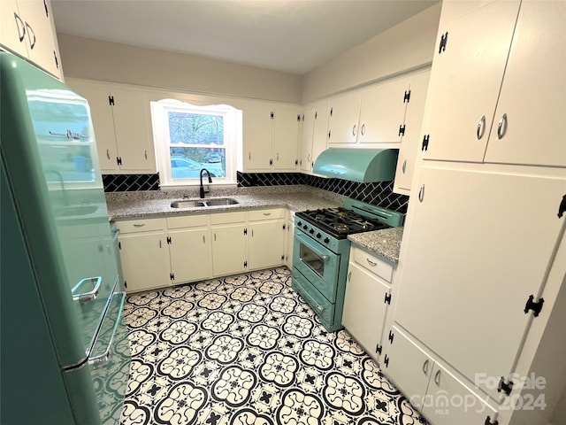 kitchen with high end stove, tasteful backsplash, refrigerator, sink, and white cabinets